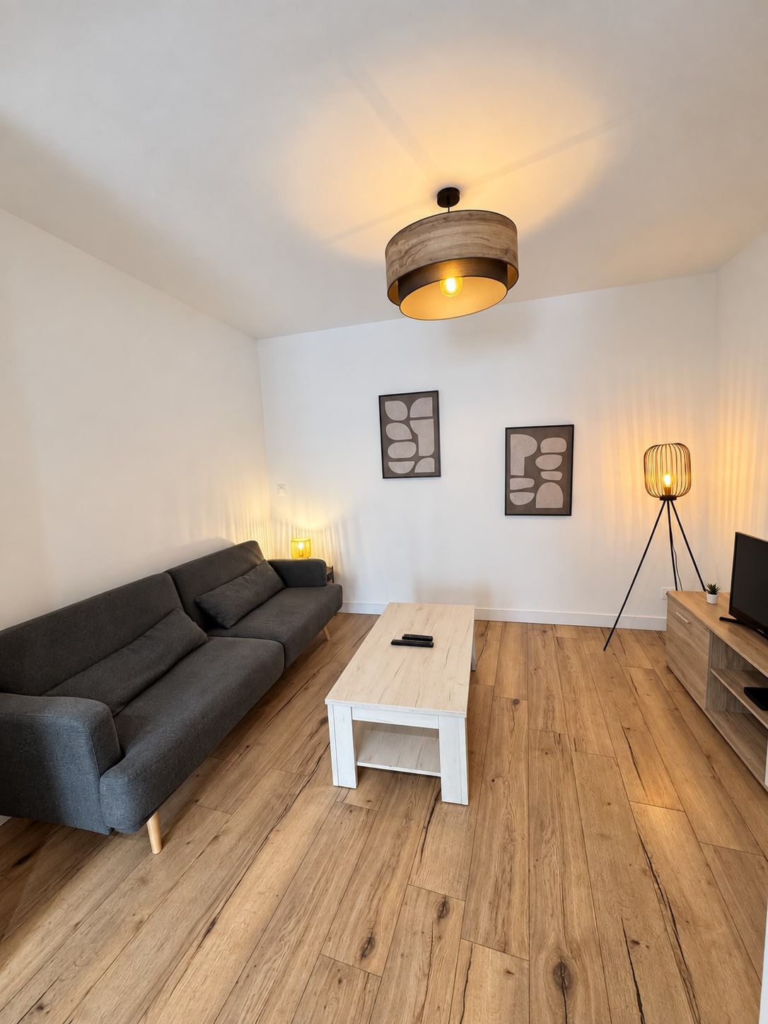 Coin salon du duplex avec canapé gris foncé, table basse, meuble télé et lampadaire