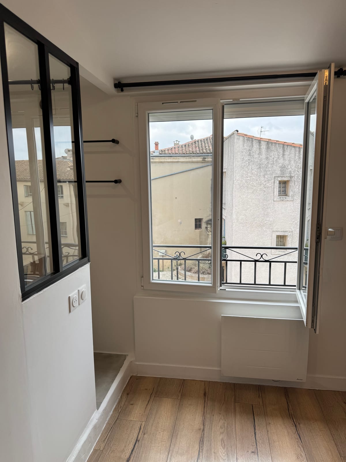 Duplexzimmer mit schwarzem Fenster und offenem Fenster auf den Dächern des Dorfes