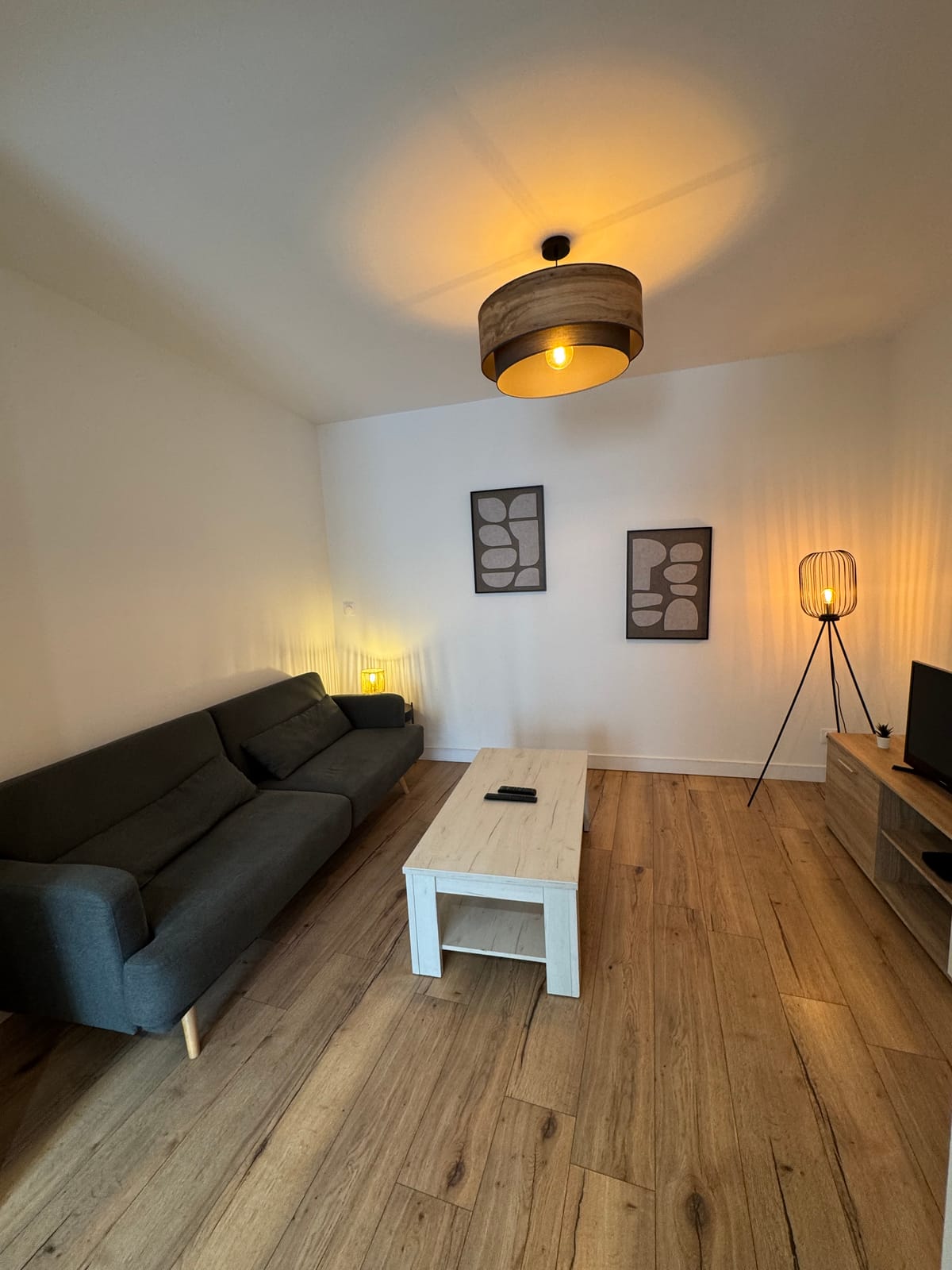 Duplex-Lounge-Bereich mit dunkelgrauem Sofa, Couchtisch, TV und Stehlampe